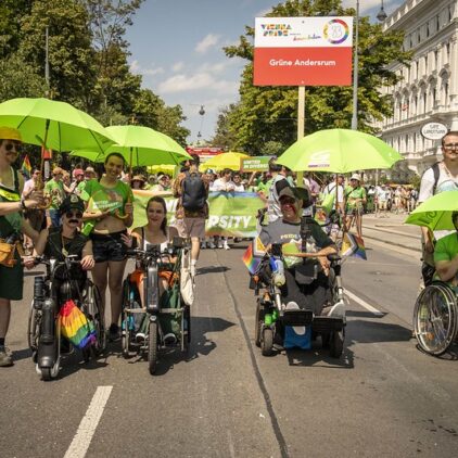 Menschen mit grünen Schirmen auf der Regenbogenparade